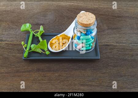 Spa herbal (white frangipani flowers, turmeric powder in white spoon ,pill,Cissus Quadrangularis Linn) on wooden background Stock Photo