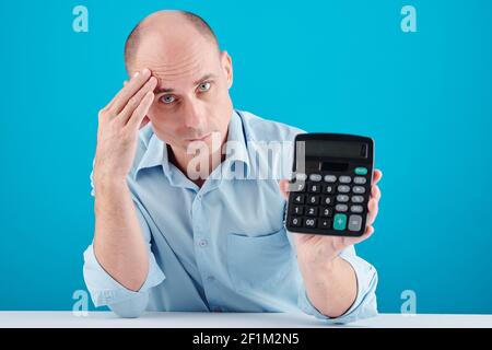 Tired stressed frowning mature bald man showing calculator, personal finances concept Stock Photo