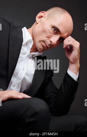 Portrait of handsome serious mature businessman thinking and looking at canera Stock Photo