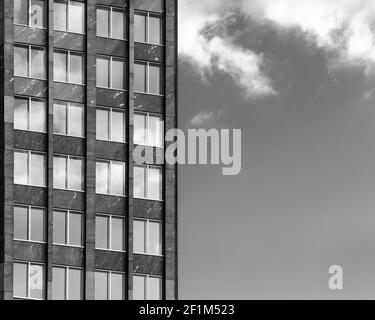 Black and white image of the facade of a building against a sky with clouds. Stock Photo