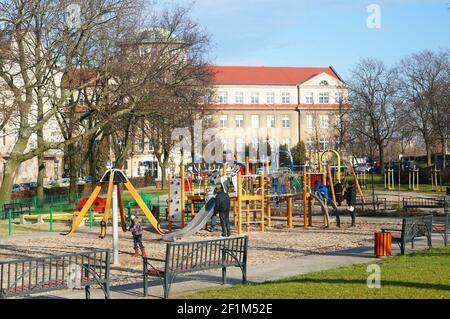 POZNAN, POLAND - Jan 31, 2016: POZNANParents with children by a play groind close to a building near the city center Stock Photo