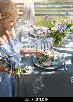 Girl decorating table in garden with flowers Stock Photo