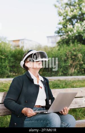 Woman on bench using VR headset Stock Photo