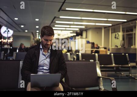 Businessman at airport using laptop Stock Photo