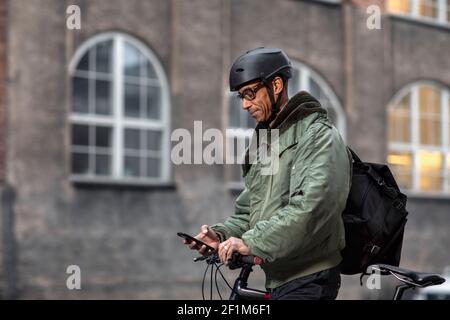 Bicycle courier using cell phone Stock Photo