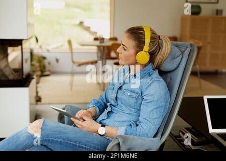 Woman sitting in armchair and using digital tablet Stock Photo
