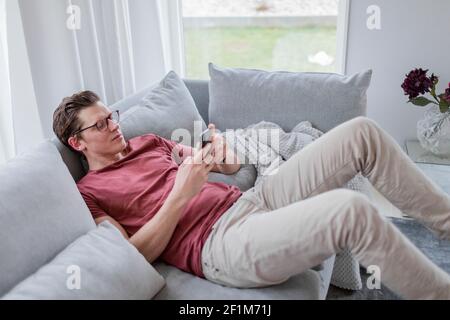 Man on sofa using cell phone Stock Photo