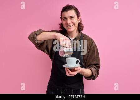 https://l450v.alamy.com/450v/2f1m73h/male-waiter-pouring-delicious-coffee-into-cup-handsome-guy-recommending-you-to-taste-this-sort-of-coffee-wearing-apron-isolated-over-pink-vivid-color-2f1m73h.jpg