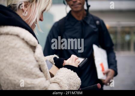 Bicycle courier taking sign from female customer while delivering package Stock Photo