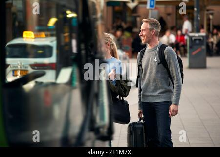 Smiling man seen from behind bus Stock Photo