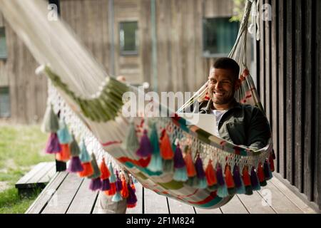 Smiling man using laptop while relaxing on hammock Stock Photo