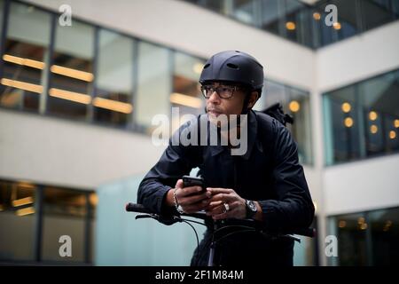 Bicycle courier using cell phone Stock Photo