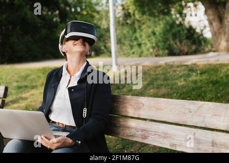 Woman on bench using VR headset Stock Photo