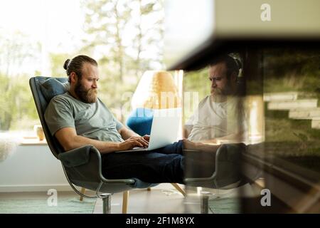 Man sitting on chair and using laptop Stock Photo