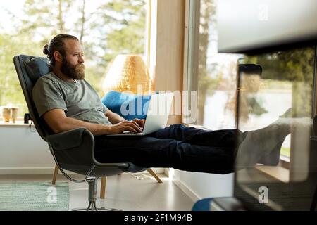 Man sitting on chair and using laptop Stock Photo