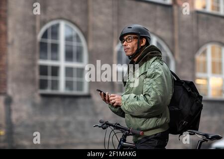 Bicycle courier using cell phone Stock Photo