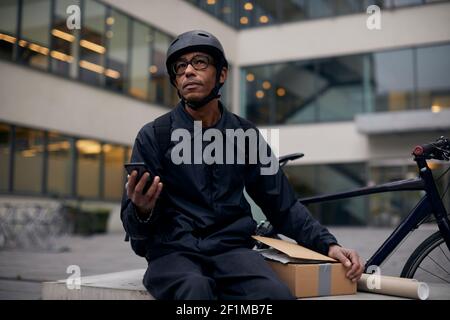 Bicycle courier using cell phone Stock Photo