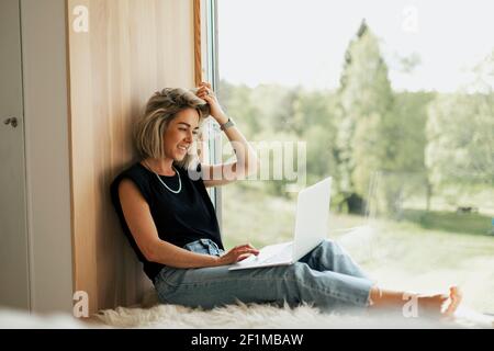 Woman using laptop near window Stock Photo