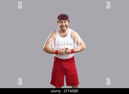 Happy man in tank top and shorts smiling and flexing his arms showing his muscles Stock Photo