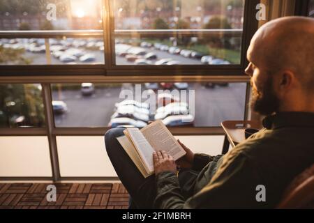 Man reading book on balcony Stock Photo