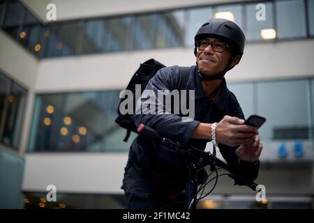 Bicycle courier using cell phone Stock Photo