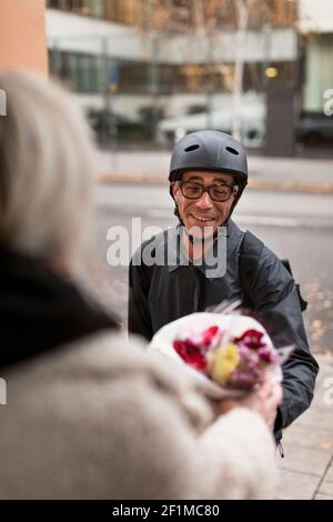 Smiling bicycle courier delivering flowers Stock Photo