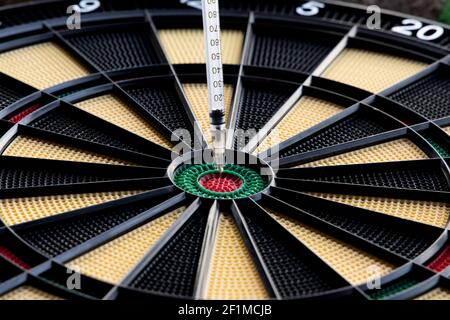 A closeup of dartboard with syringe in the red center, bulls eye. A concept for corona virus pandemic and mass vaccination  in the world. Stock Photo