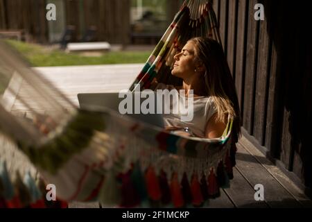 Woman lying in hammock with laptop Stock Photo