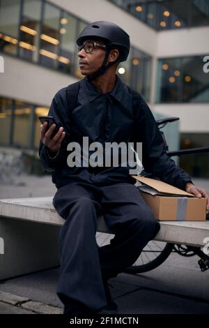 Bicycle courier using cell phone Stock Photo