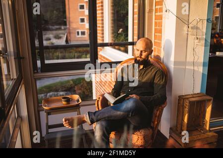 Man reading book on balcony Stock Photo