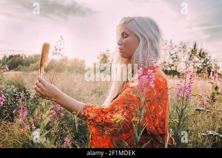 Young woman with feather in meadow Stock Photo