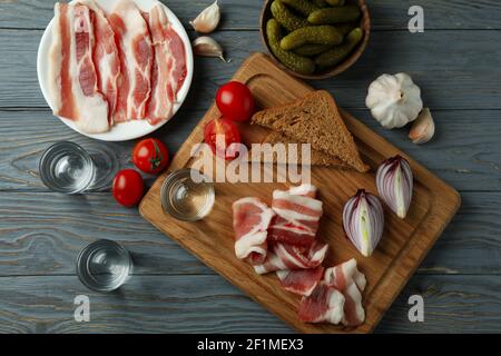 Shots of vodka and tasty snacks on gray wooden background Stock Photo