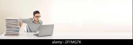 Office manager working on laptop instead of dealing with piles of papers, copy space banner Stock Photo