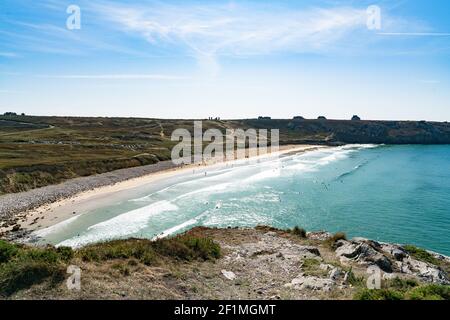 A view of the Plage de Pen Hat beach and bay with many surfers surfing on  a beautiful summer day on Stock Photo