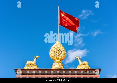 Dharma wheel and Chinese flag waving at Songzanlin Tibetan Buddhist monastery in Shangri-La Yunnan China Stock Photo