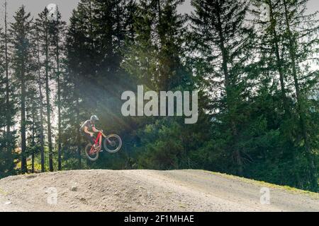 Downhill mountain biker jumping high and riding hard in Lenzerheide in the Swiss Alps Stock Photo