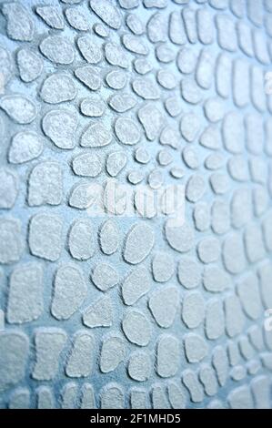 Shiny light blue backdrop with imitation reptile's skin. Texture covering for wall by decorative plaste crocodile skin effect. Stock Photo