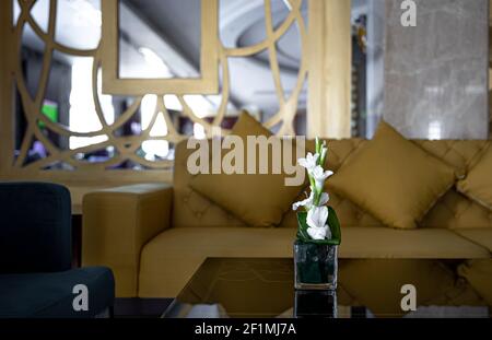 Living room interior with cozy sofas and a table with a bouquet of lilies. Stock Photo