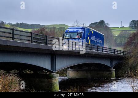 Distribution & transportation in bad rainy weather (raining) - lorry (HGV) travelling over river bridge, spraying water - A59, Yorkshire, England, UK. Stock Photo