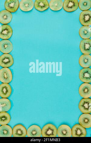 Bright blue background and frame made of thin juicy kiwi slices Stock Photo