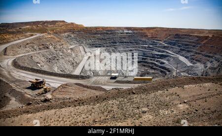 Copper ore open-pit mining. Quarry dump truck and excavator on road down in quarry. Stock Photo