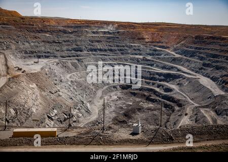 Copper ore open-pit mining (quarry) in steppe. White gravel road. Blue sky background. Stock Photo