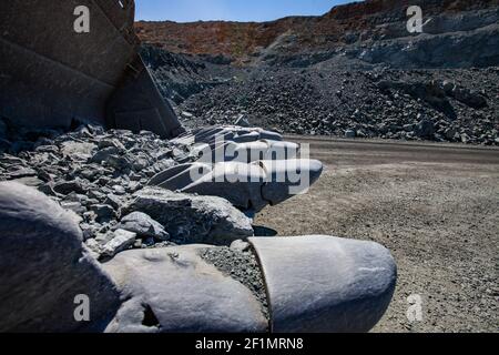 Bulldozer bucket steel teeth close up. Quarry and blue sky on background. Stock Photo