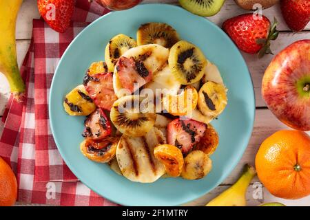 GRILLED FRUIT on a blue plate and white wooden background Stock Photo