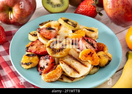 GRILLED FRUIT on a blue plate and white wooden background Stock Photo