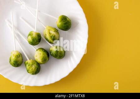 Set of brussel sprouts with lollipop sticks on yellow background Stock Photo