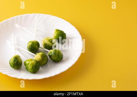 Set of brussel sprouts with lollipop sticks on yellow background Stock Photo