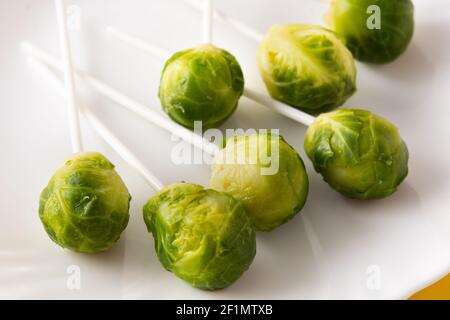 Set of brussel sprouts with lollipop sticks on yellow background Stock Photo
