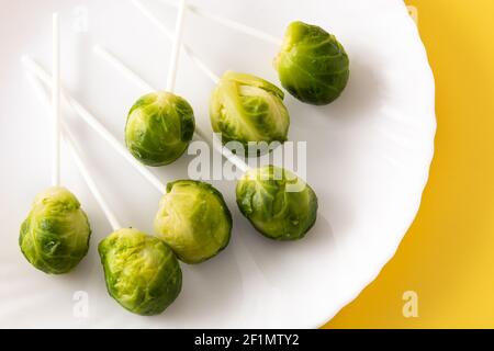 Set of brussel sprouts with lollipop sticks on yellow background Stock Photo