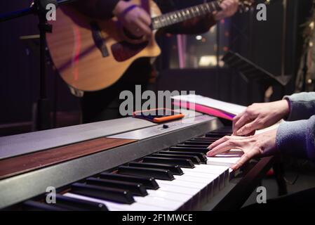 The pianist and guitarist are playing. Music recording or rehearsal concept. Stock Photo